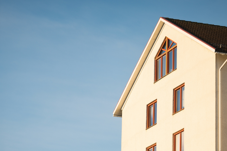Close-up of a modern residential building with multiple windows under a clear blue sky, representing property investment or below market value (BMV) opportunities.