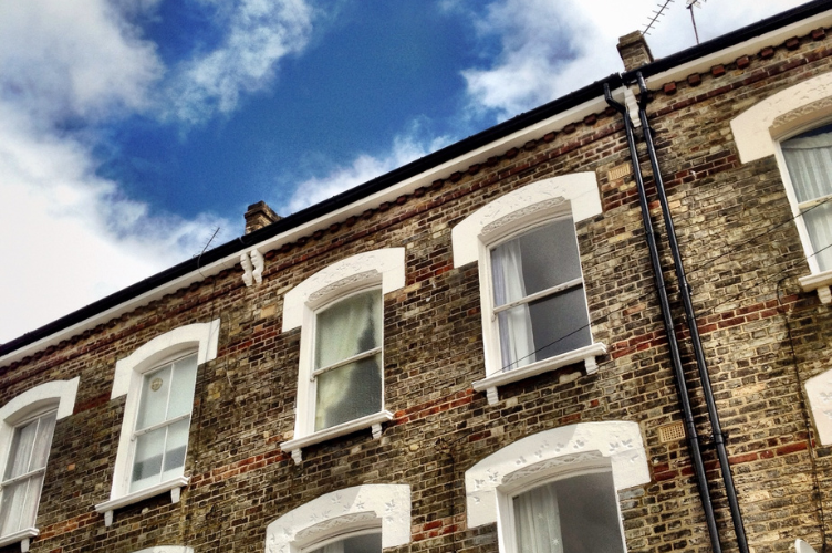Close-up of a traditional brick residential building with multiple windows, representing housing or property investment.