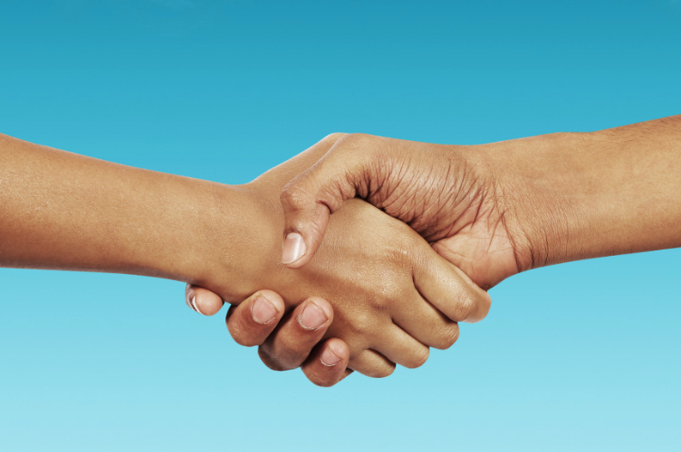 Close-up of two hands shaking against a clear blue background, symbolizing trust and agreement.